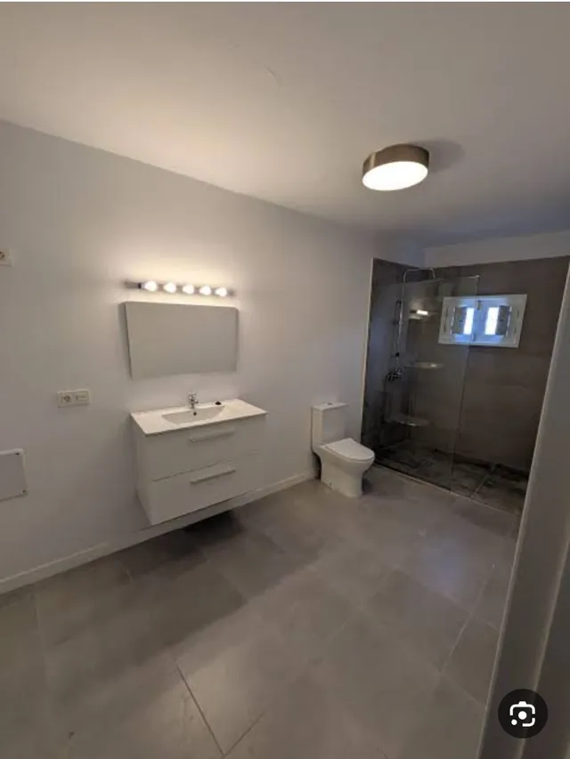 Baño en gris con ducha a ras de suelo y mampara de cristal