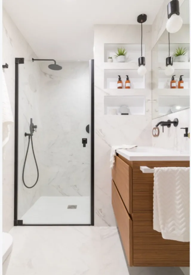 Baño moderno con mampara de ducha, estanterías empotradas y mueble de lavabo en madera