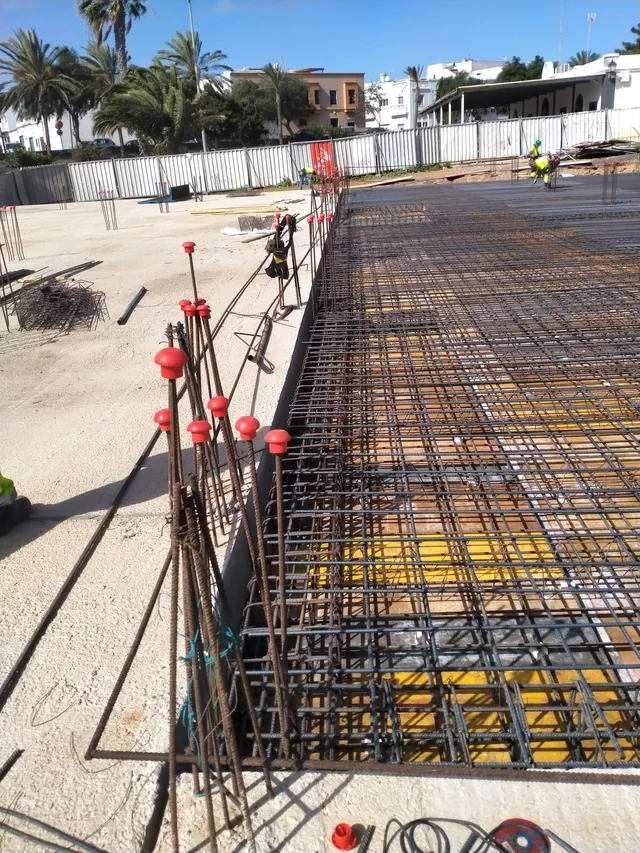 Esperas de pilares con tapones rojos junto al mallazo de un forjado