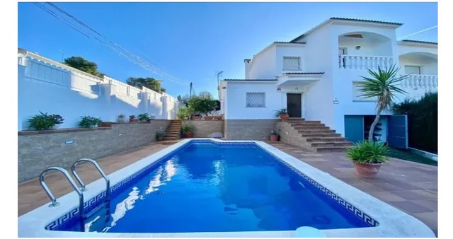 Piscina en el patio de una vivienda con escalera de acceso y zona ajardinada