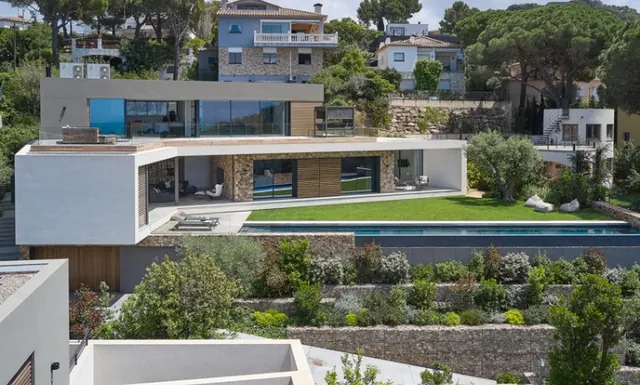 Vivienda moderna en ladera con piscina alargada y césped junto a la terraza